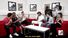 a group of people are sitting in a room with mtv news signs on the wall