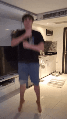a man in a black shirt and blue shorts dancing in a living room