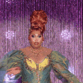 a drag queen with red hair and a green and gold dress
