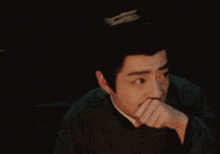 a man with a crown on his head is making a funny face with his hand on his chin .