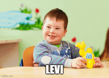 a little boy with down syndrome is sitting at a table holding a toy and the name levi is on the table