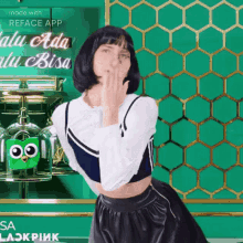 a woman blowing a kiss in front of a green wall that says reface app