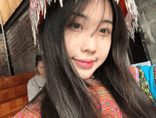 a woman wearing a colorful dress and a headdress looks at the camera with a smile on her face