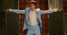a man in a blue suit and white shirt is dancing in front of a door .