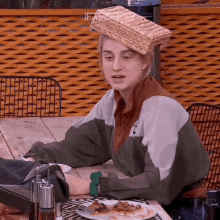 a woman sitting at a table with a basket on her head