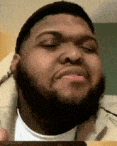 a man with a beard is making a funny face with his eyes closed and his mouth open .