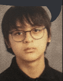 a young boy with glasses and a black shirt