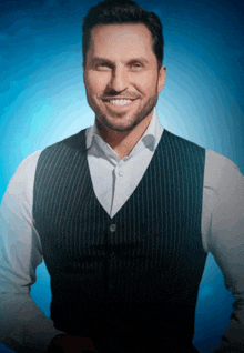 a man wearing a vest and a white shirt is smiling