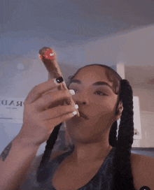 a woman with pigtails is smoking a cigarette in front of a sign that says ' daa ' on it