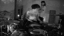 a man wearing a shirt that says knockedhouse is playing drums