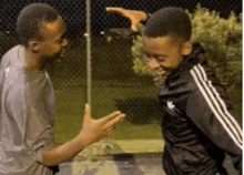 a man and a boy are standing next to each other and the boy is wearing a black adidas jacket