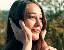 a close up of a woman covering her ear with her hands