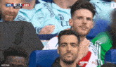 a man wearing an arsenal shirt sits in the stands