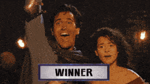 a man and a woman are standing next to each other with a sign that says winner