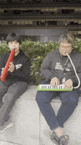 a man wearing a neon genesis evangelion sweatshirt plays a green keyboard