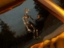a painting of a robot hanging from a window with trees in the background