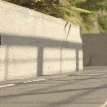 a person is riding a skateboard down a street in front of a concrete wall .