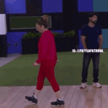 a woman in a red suit is walking on a wooden floor .