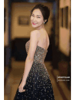 a woman in a black and gold dress is standing in a hallway
