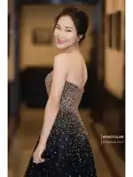 a woman in a black and gold dress is standing in a hallway