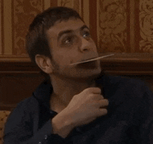 a man is holding a piece of paper in his mouth and eating it .