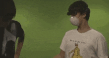 a man wearing a mask and gloves is holding a stick in front of a green background .
