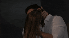 a man and woman are kissing in a dark room .