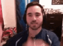 a man with a beard is wearing headphones and making a face .