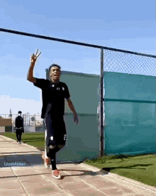 a soccer player with the number 2 on his shorts is giving the peace sign
