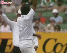 a man in a white shirt is throwing a ball in the air while a referee watches .