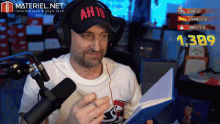 a man wearing headphones and a hat that says ah19 is reading a book