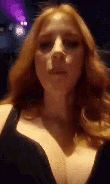 a woman with red hair is wearing a black bra and making a face