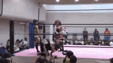 a woman is wrestling another woman in a ring while a crowd watches .