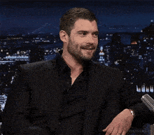 a man with a beard is wearing a black suit and black shirt .