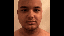 a man with a shaved head and a beard looks at the camera