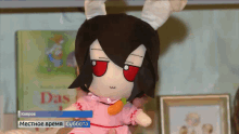 a stuffed doll with a carrot in her mouth is on display in front of a book titled das
