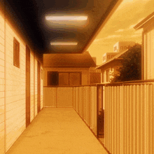 a hallway between two buildings with a fence and a balcony