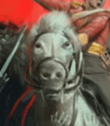 a man in a red jacket is riding a white horse with a sword .