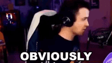 a man wearing headphones is sitting in a chair in front of a microphone with the words obviously written on the screen .