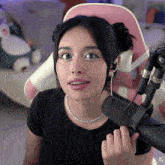 a woman wearing headphones and a black shirt is holding a microphone with xg written on the bottom right