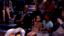 a man and a little girl are sitting in a theatre applauding