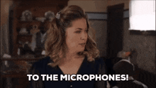 a woman says " to the microphones " while holding a microphone