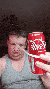 a man is holding a can of coca cola