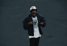a man wearing a black jacket and a white shirt with a picture of a man on it is dancing