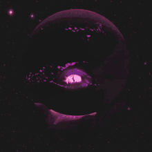 a hand is holding a pink planet with an eye in the middle
