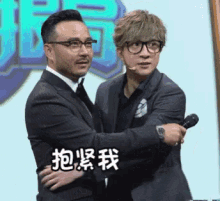 a man in a suit and tie is hugging another man in a suit
