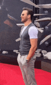 a man is standing on a red carpet with his hands in his pockets