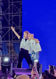 a couple of people standing on a stage with a blue backdrop