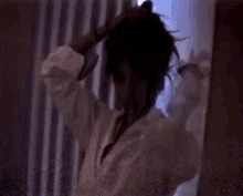 a woman is standing in front of a mirror looking at her hair .