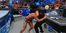 two men are wrestling in a wrestling ring while a crowd watches .